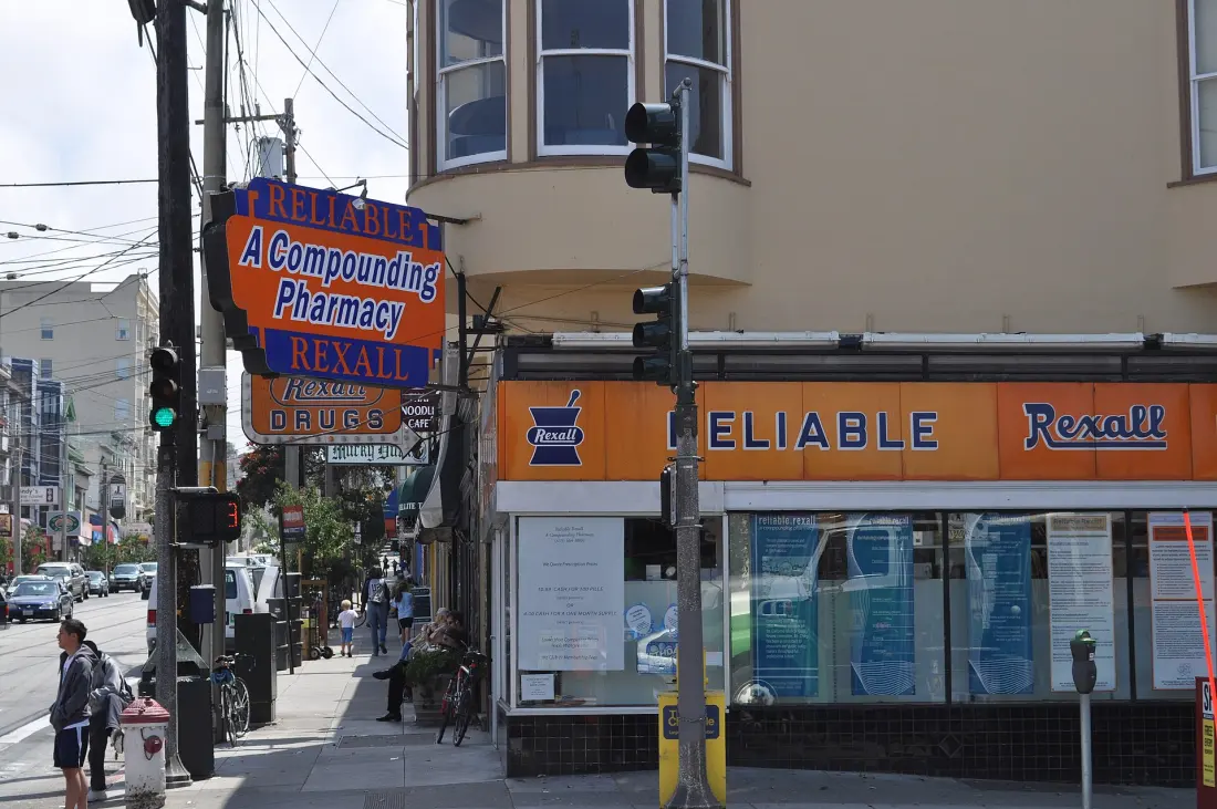 The orange Reliable Rexall pharmacy sign on the corner of 9th Avenue and Irving Street