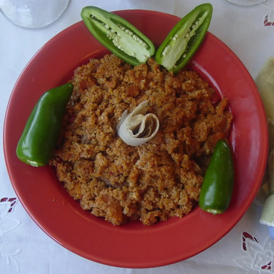 A red plate of taita fit-fit ringed with green chillies